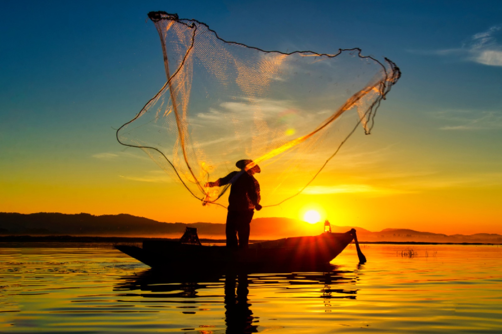 Fisherman casting his net at sunset